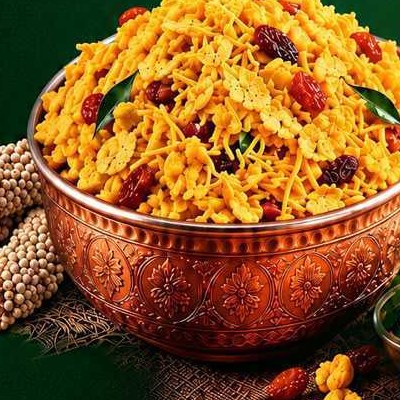 Montello Suvarnakan Chivda heaped in a copper bowl with raisins and curry leaves